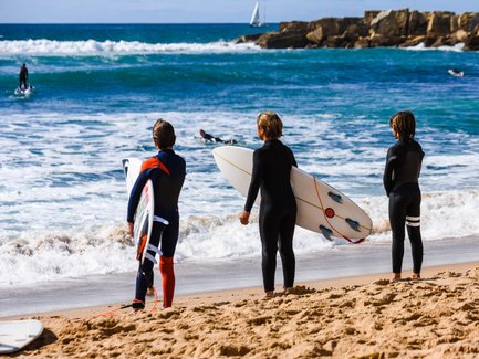 Drei Kinder warten auf die nächste Welle zum surfen