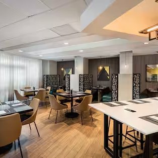 Ein modernes Restaurant mit eleganten Tischen und Stühlen, das eine einladende Atmosphäre ausstrahlt.