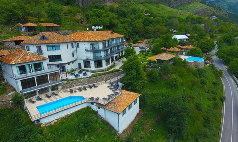 Ein malerisches Resort mit mehreren Gebäuden, umgeben von üppigem Grün und einem einladenden Poolbereich.