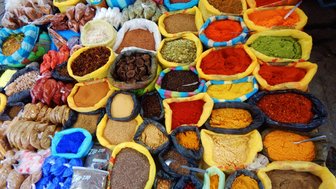 Bunte Gewürze in verschiedenen Behältern auf einem Markt, die eine Vielzahl von Farben und Texturen zeigen.