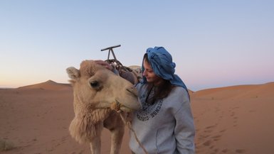 Jugendliche zeigt liebevolle Geste beim Streicheln eines Kamels – Marokko Familienreise