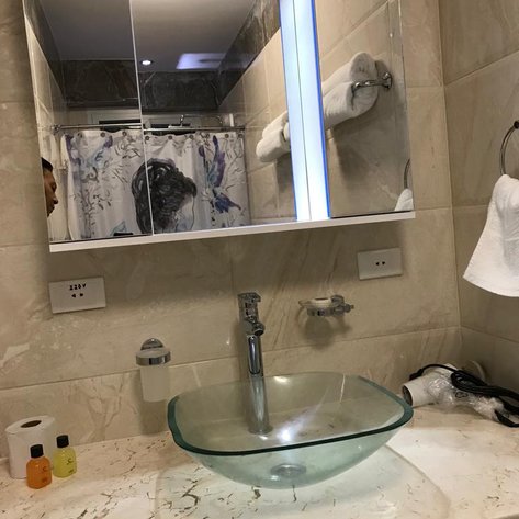 Ein modernes Badezimmer mit einem eleganten, gläsernen Waschbecken und einem großen Spiegel, der die Umgebung reflektiert.