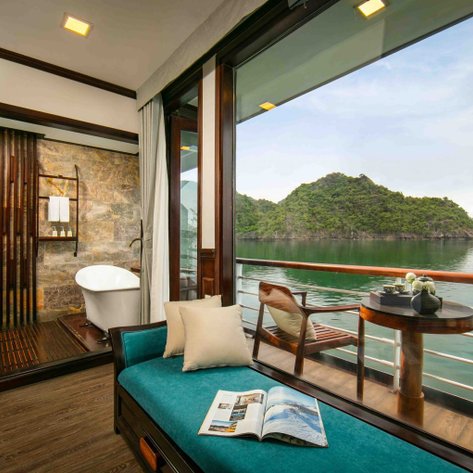 Ein elegantes Zimmer auf einem Kreuzfahrtschiff mit Blick auf die ruhige Halong-Bucht und üppige grüne Hügel.