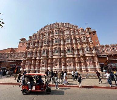 Das Hawa Mahal in Jaipur zeigt eine beeindruckende Fassade mit vielen Fenstern und kunstvollen Details, umgeben von Menschen.