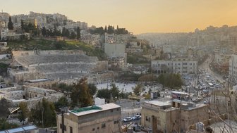 Das römische Theater in Amman ist von modernen Gebäuden umgeben, während die Sonne hinter den Hügeln untergeht.