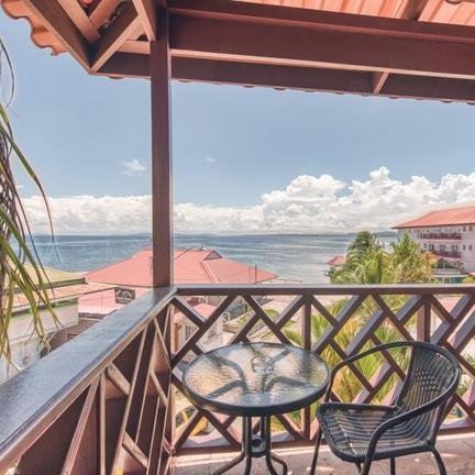 Ein Balkon mit einem Tisch und einem Stuhl bietet einen atemberaubenden Blick auf das Meer und die Wolken am Himmel.
