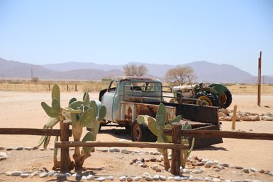 Ein rostiges Auto und ein rostiger Trecker stehen verlassen in der Wüste - Namibia mit Kindern