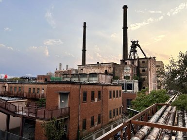 Eine alte Industrieanlage mit hohen Schornsteinen und verwitterten Ziegelgebäuden unter einem bewölkten Himmel.