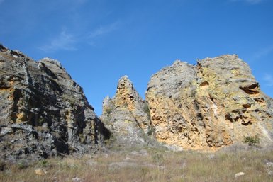 Im Isalo-Nationalpark erheben sich majestätische Felsen unter einem strahlend blauen Himmel, umgeben von trockenem Gras.
