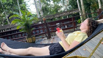 Mädchen liegt entspannt in einer farbenfrohen Tuchhängematte im Grünen – Malaysia & Borneo Familienreise