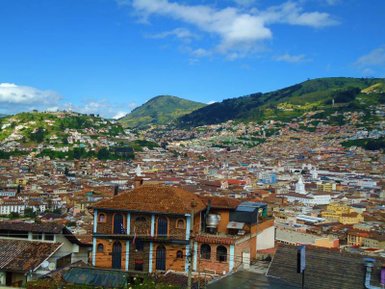 Ein atemberaubender Blick auf Quito, mit bunten Häusern und grünen Hügeln unter einem strahlend blauen Himmel.