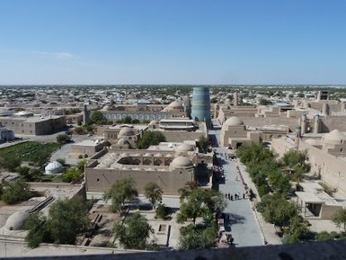 Ein Blick auf die Altstadt von Itchan Kala, mit traditionellen Lehmhäusern und einer belebten Straße voller Menschen.