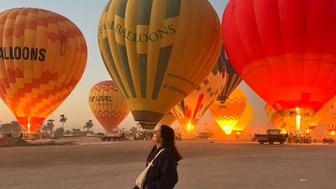 Teenager steht vor Heißluftballons in der Morgendämmerung – Ägypten Reise mit Kindern