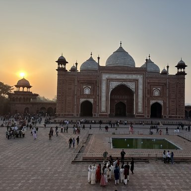 Die majestätische Taj Mahal erstrahlt im Sonnenuntergang, umgeben von Besuchern, die die Schönheit des Denkmals bewundern.