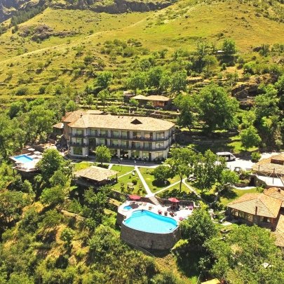 Ein malerisches Resort in den Bergen, umgeben von üppigem Grün und mit einem einladenden Pool im Vordergrund.
