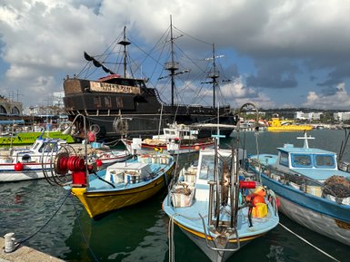 Im Hafen von Limassol liegen bunte Fischerboote vor dem beeindruckenden Piratenschiff 'Black Pearl'.