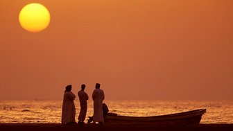 Omanis beobachten den Sonnenuntergang am Strand im Oman – Oman Reise mit Kindern