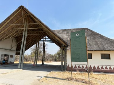 Der Eingang zum Moremi Game Reserve zeigt ein traditionelles Dach und ein Willkommensschild mit wichtigen Informationen.