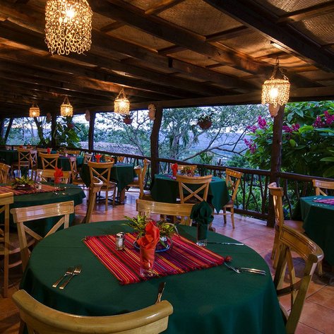 Ein einladendes Restaurant mit Holztischen, grünen Tischdecken und bunten Blumen im Hintergrund, ideal für ein romantisches Abendessen.