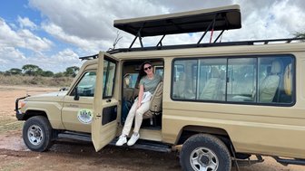 Teenagerin sitzt im Jeep und posiert für ein Foto im Tarangire-Nationalpark – Tansania Reise mit Kindern