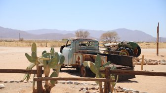 Ein rostiges Auto und ein rostiger Trecker stehen verlassen in der Wüste - Namibia mit Kindern