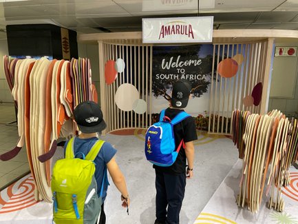 Zwei Kinder kommen mit Gepäck am Flughafen in Südafrika an – Südafrika Familienreise