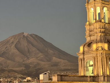 Die majestätische Silhouette des Misti-Vulkans erhebt sich hinter der prächtigen Kirche in Arequipa, beleuchtet von der Abenddämmerung.
