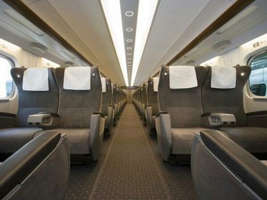Der Innenraum eines modernen Zuges mit bequemen Sitzen und einem klaren, hellen Design, das eine entspannte Atmosphäre schafft.