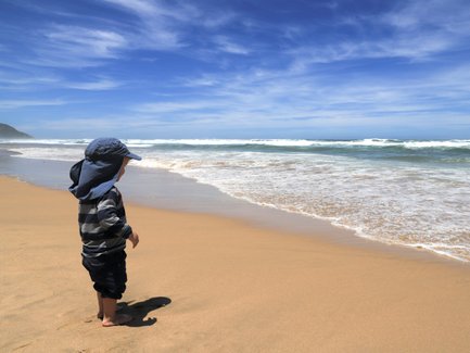 Kind steht an der Küste und blickt aufs Meer – Garden Route mit Kindern