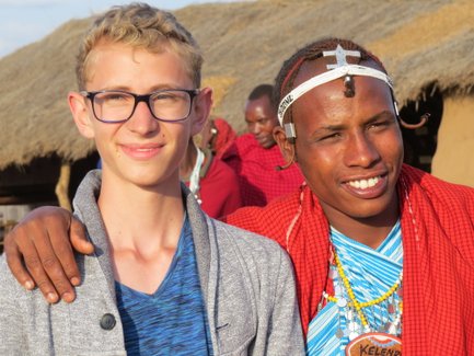 Junge begegnet einem Massai bei einem Dorfausflug – Tansania Familienreise