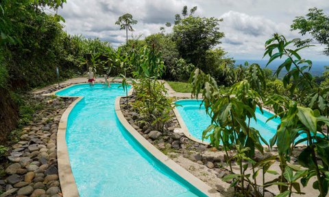 Ein malerischer Pool mit klarem Wasser schlängelt sich durch eine grüne Landschaft, umgeben von üppiger Vegetation.