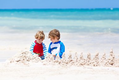 Zwei Kinder formen gemeinsam eine Sandburg am Strand von Playa del Carmen – Mexiko Reise mit Kindern