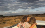 Zwei Kinder sitzen auf der Fensterbank eines Autos und genießen die Aussicht auf eine weite, offene Landschaft.