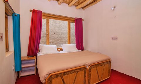 Ein gemütliches Zimmer mit einem großen Bett, umgeben von bunten Vorhängen und einem rustikalen Holzdecke.