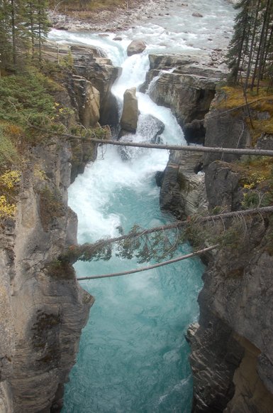 Ein beeindruckender Wasserfall stürzt in eine enge Schlucht, umgeben von steilen Felsen und üppigem Grün.