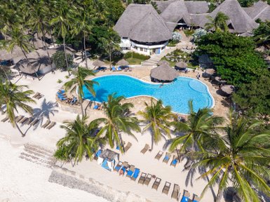 Ein tropisches Resort mit einem glitzernden Pool, umgeben von Palmen und Sonnenliegen am weißen Sandstrand.