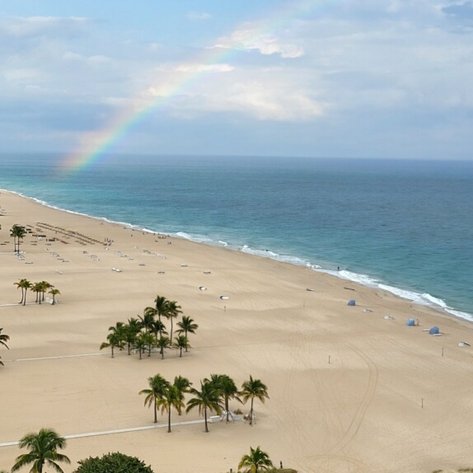 Ein Regenbogen spannt sich über den Himmel, während sanfte Wellen an den goldenen Strand von Fort Lauderdale schlagen.