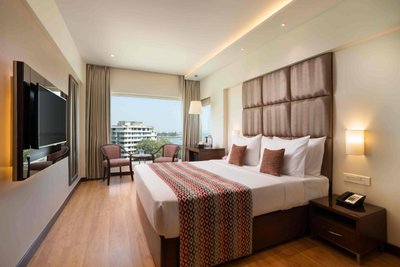Ein modernes Hotelzimmer mit einem großen Bett, eleganten Kissen und einem Fernseher an der Wand, das Gemütlichkeit ausstrahlt.