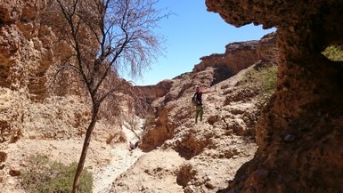 Ein Kind sitzt zwischen großen Felsen in der Landschaft - Namibia Urlaub mit Kindern