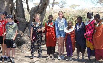 Kinder aus Reisegruppe posieren gemeinsam mit einer Massai-Familie – Tansania Familienreise