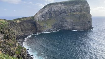 Eine beeindruckende Küstenlandschaft mit steilen Klippen, die ins tiefblaue Meer fallen, unter einem klaren Himmel.