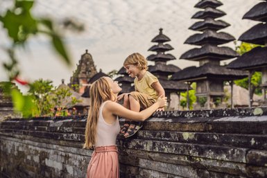 Mutter mit Kind beim Besuch eines balinesischen Tempels – Bali Familienreise