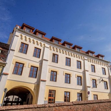 Die Fassade eines eleganten Hotels mit großen Fenstern und einem klaren blauen Himmel im Hintergrund.