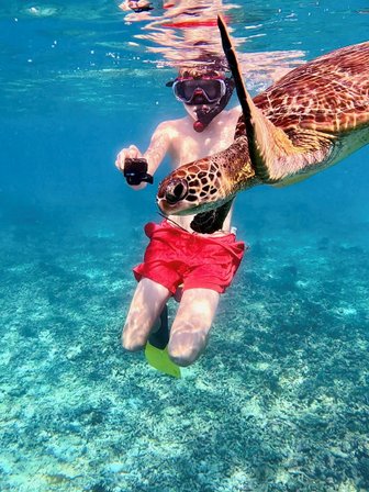 Junge entdeckt eine Meeresschildkröte unter Wasser im Oman – Oman Familienreise