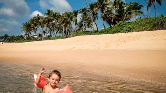 Kleinkind planscht fröhlich im Meerwasser – Sri Lanka Reise mit Kindern