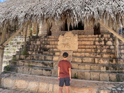 Kind bestaunt alte Steingravuren an einer Tempelstruktur in Ek Balam – Mexiko Familienreise