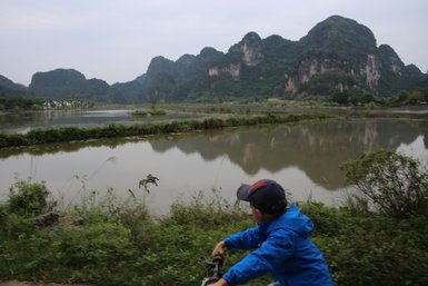 Junges Kind fährt Fahrrad entlang der Küste der Halong-Bucht – Vietnam Familienreise