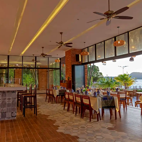 Ein elegantes Restaurant mit großen Fenstern, das einen Blick auf das Meer und die umgebende Natur bietet.