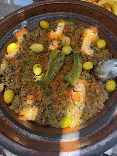 Ein rustikales marokkanisches Tajine-Gericht, gefüllt mit gewürztem Hackfleisch, Tomaten und Oliven, liebevoll angerichtet.