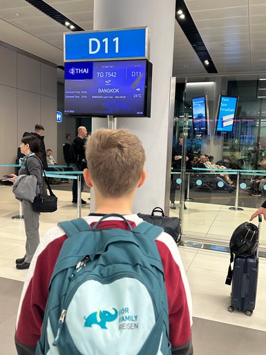 Teenager wartet am Gate auf seinen Abflug nach Bangkok – Thailand Reise mit Kindern